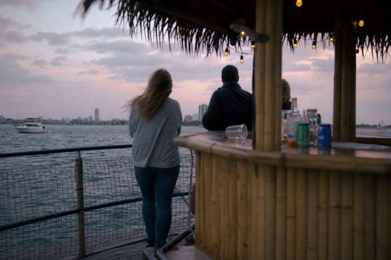 Small party boat with tiki-bar styling crossing Key West harbor at sunset