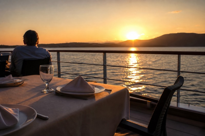 Dinner table set on the open deck of a Key West cruise boat as the sun drops toward the horizon