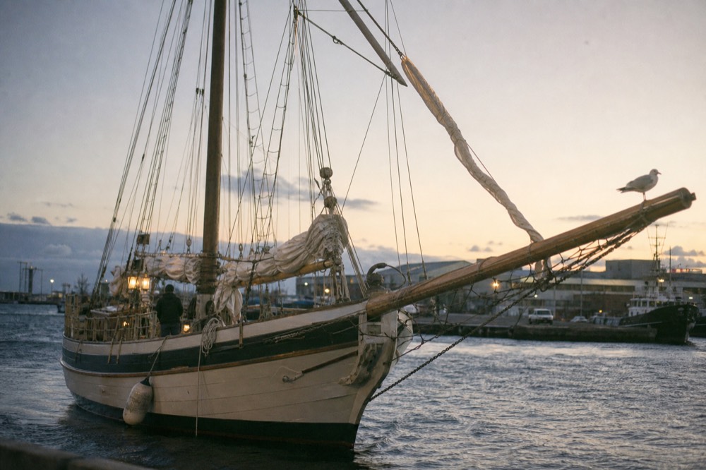 Wooden schooner under sail near the Key West Historic Seaport at dusk, no text, no logos, no people