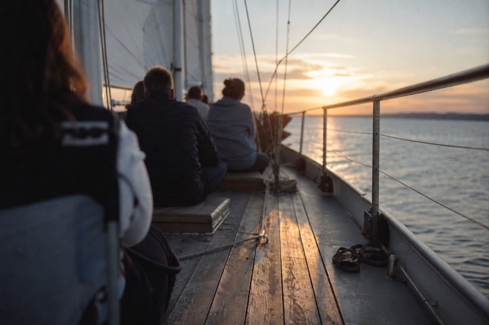 Passengers seated on a schooner deck as the sun sets over water near Key West, no text, no logos, no people.