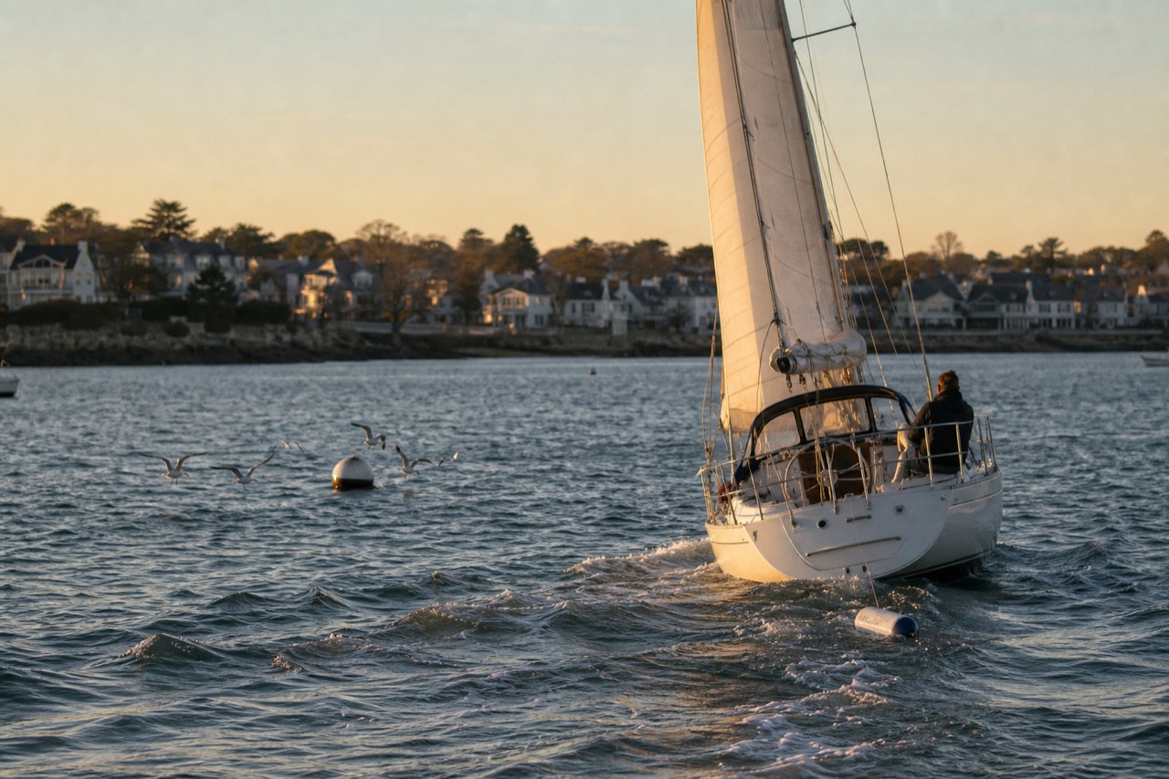 A sailboat gliding through golden evening light near the Key West shoreline, no text, no logos, no people