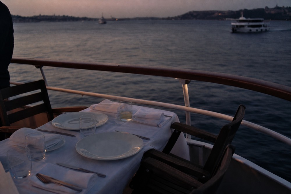 Set dinner table on a boat deck with place settings at dusk, no text, no logos, no people