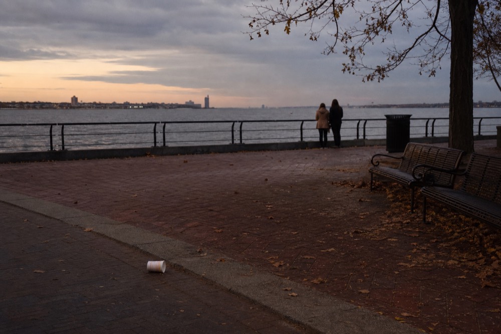 Waterfront plaza at dusk with a crowd-free view over the water and boats, no text, no logos, no people