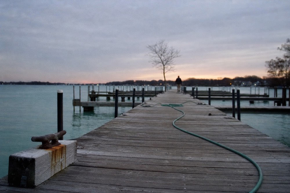 An empty wooden dock extending into calm turquoise Key West water at dusk, no text, no logos, no people.