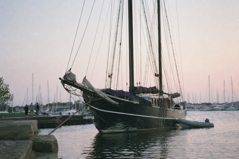 A tall sailing ship with dark sails anchored at a Key West marina in evening light, no text, no logos, no people.