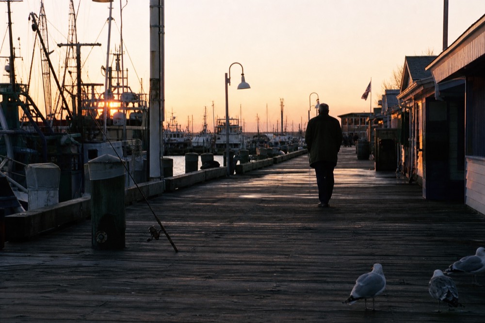 A historic Key West seaport boardwalk at dusk with sailboat masts, warm light, no text, no logos, no people