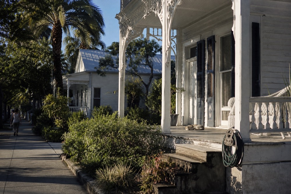 A historic white conch house with palm trees in afternoon light in Key West, no text, no logos, no people