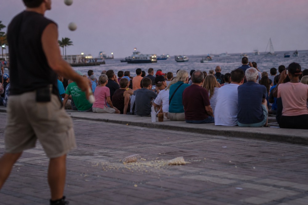 Crowds gathered along the Mallory Square seawall at dusk with street performers, no text, no logos, no people.