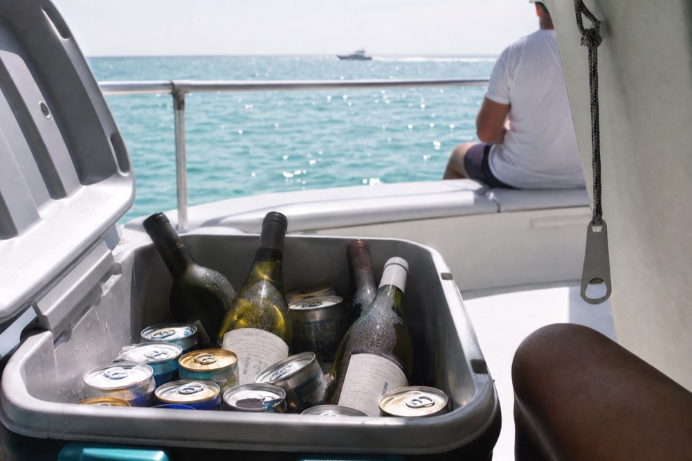 A cooler filled with beer cans and wine bottles on a boat deck, no text, no logos, no people